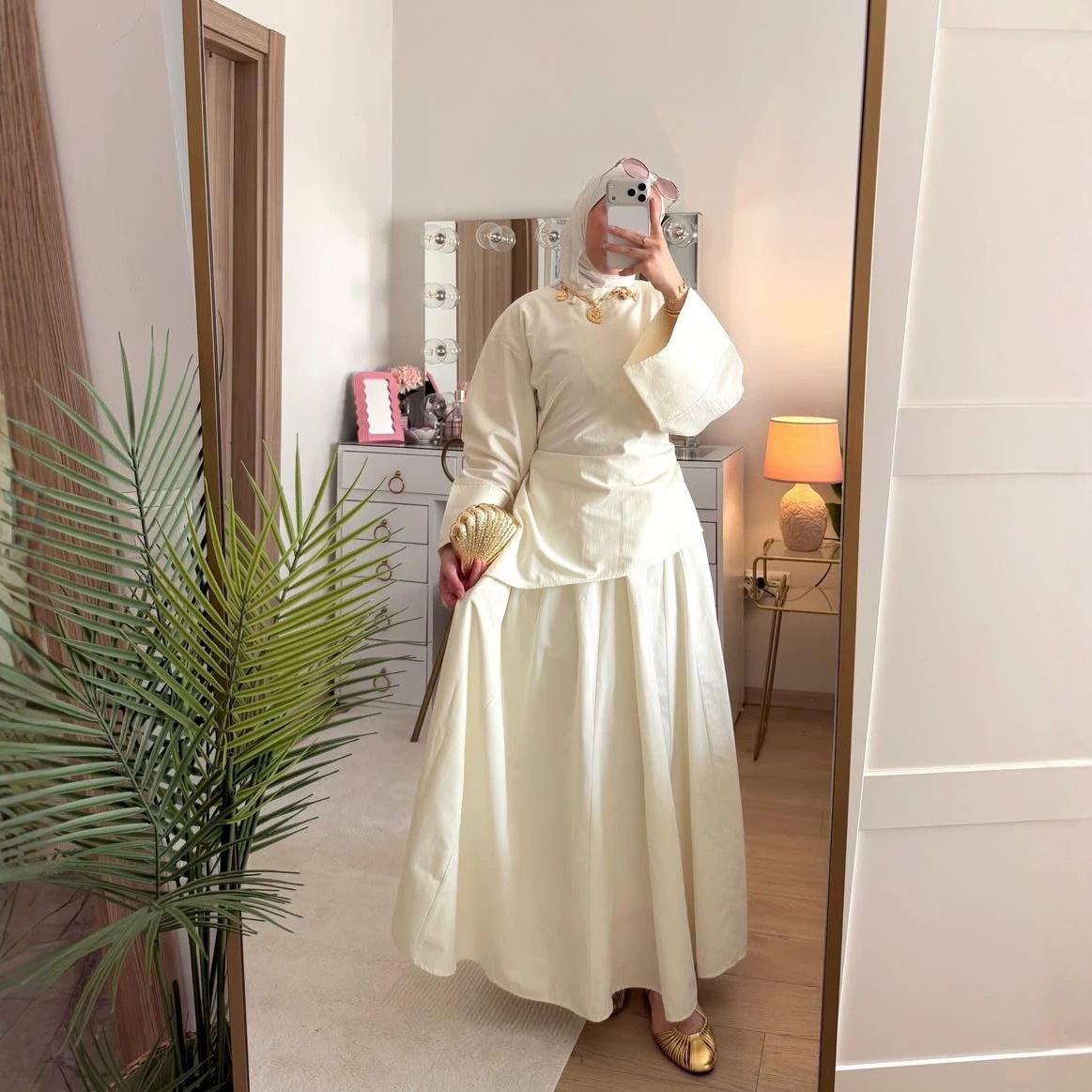 Model in a cream long-sleeve top with matching maxi skirt