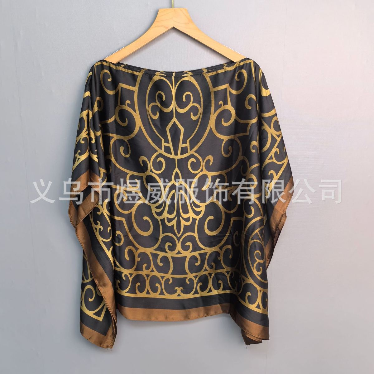 Faux-silk printed hijab scarf hanging on a wooden hanger, orange edge with floral pattern